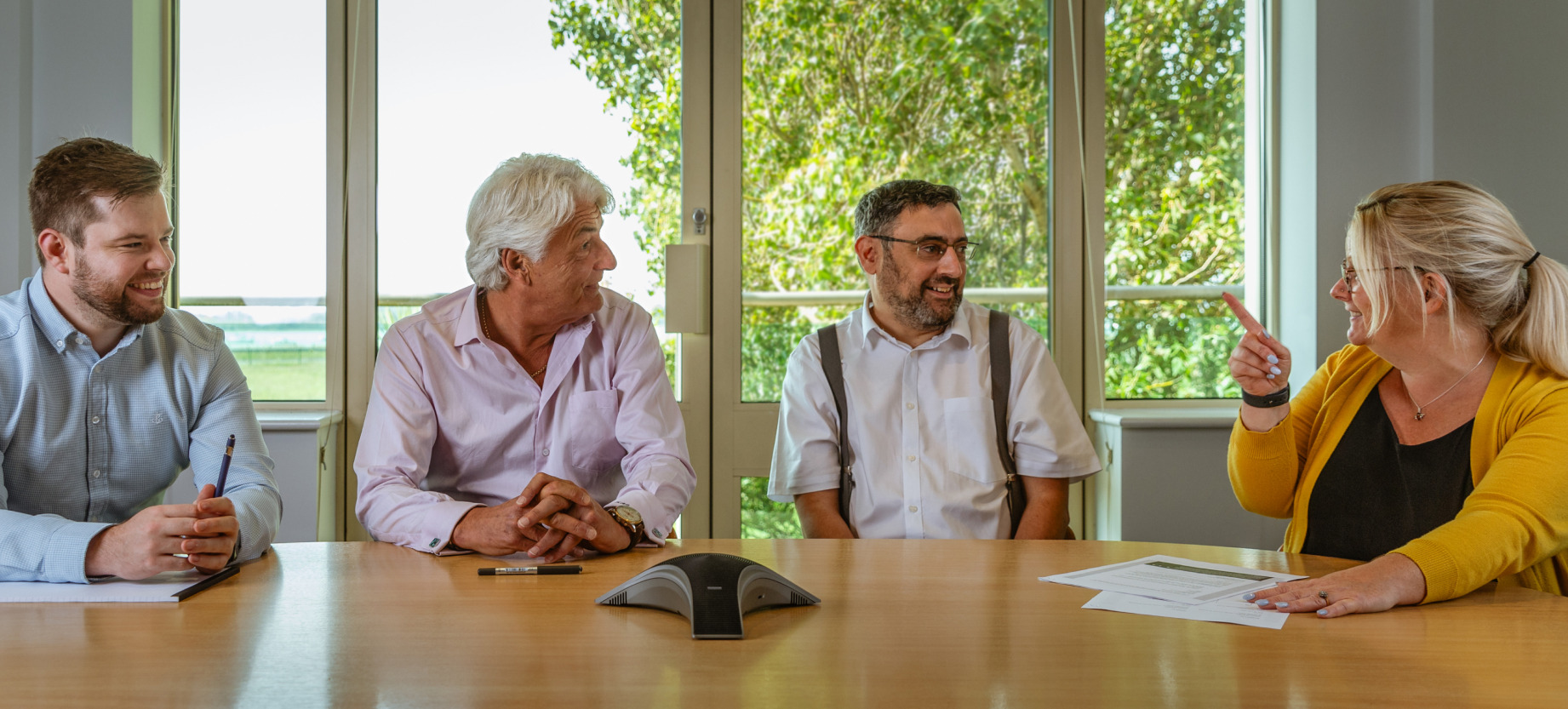 Four independent financial advisers in Poole, sat at a desk talking about financial planning.