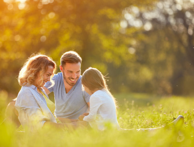 A family sat in a field, happy as they have life insurance and personal protection.