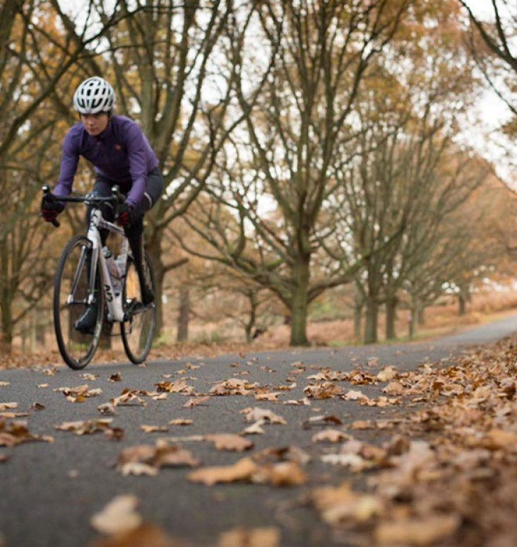 Person cycling on a path, covered in leaves.