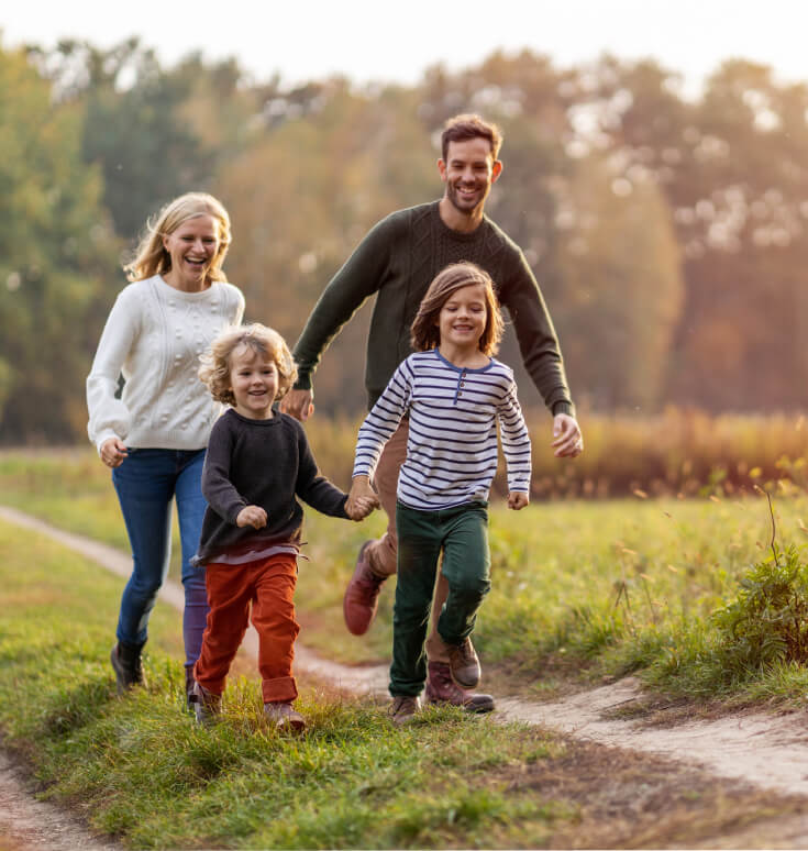 A family happily running in a field as they have personal protection insurance.